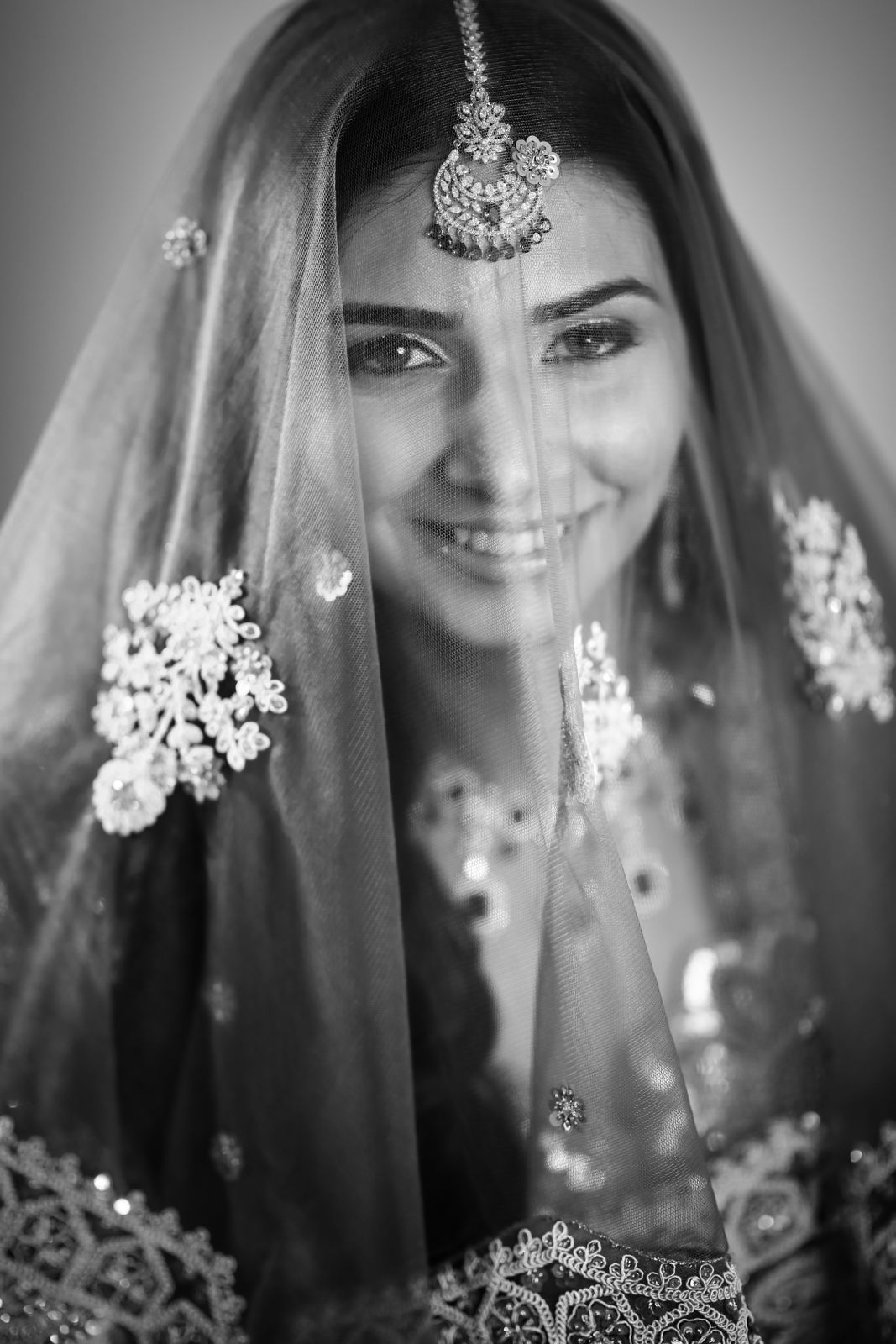 Bride smiling behind a veil in black and white